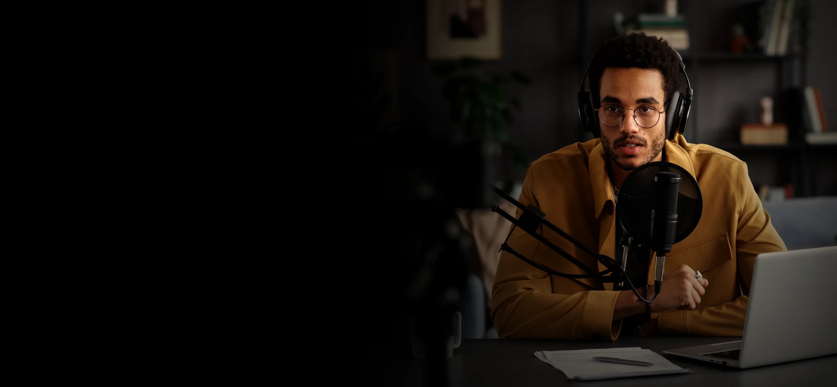 Webinar host at his desk with a microphone and laptop