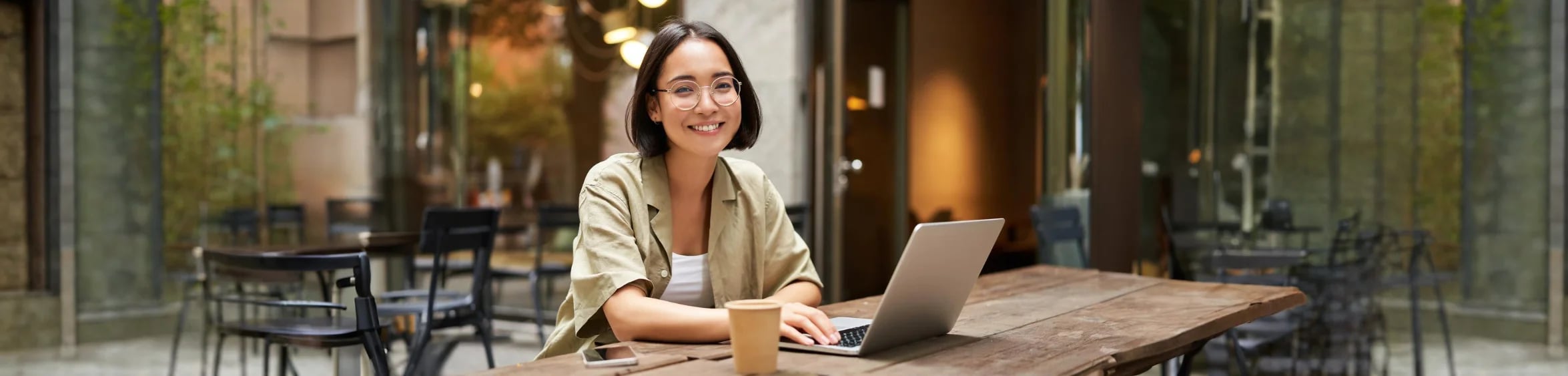 Seller presenting live on a webinar from a laptop at an outdoor café table