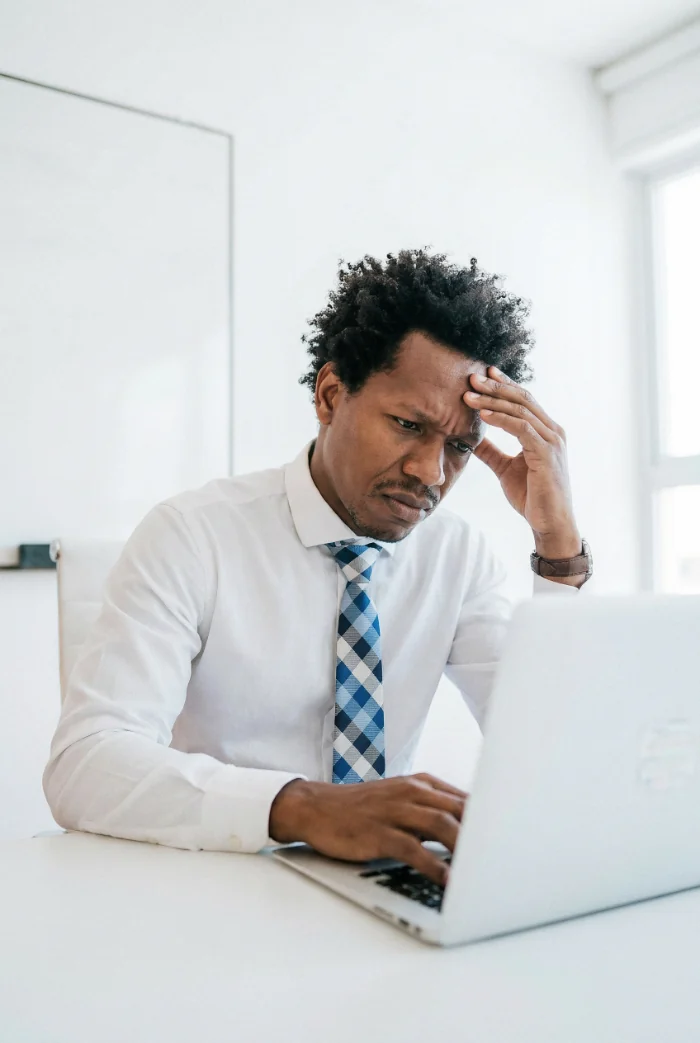 Frustrated man with his hand on his forehead looking at a laptop